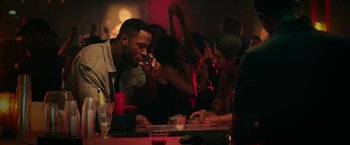Movie still from “Dope” (2015), directed by Rick Famuyiwa – A group of people sitting at a bar drinking and eating; Medium shot, Over the shoulder angle