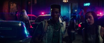 Movie still from “Dope” (2015), directed by Rick Famuyiwa – A young man with a mohawk is standing in front of a police car; Close Up shot, Over the shoulder angle