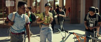 Movie still from “Dope” (2015), directed by Rick Famuyiwa – A person standing in front of a group of people; Medium shot, Over the shoulder angle