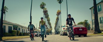 Movie still from “Dope” (2015), directed by Rick Famuyiwa – A group of people riding bikes down a street; Wide shot, Low angle