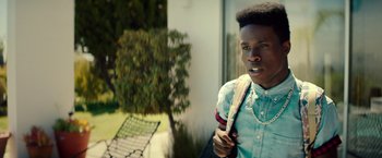 Movie still from “Dope” (2015), directed by Rick Famuyiwa – A young man holding a bag in front of a tree; Close Up shot, Over the shoulder angle