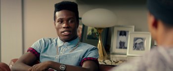 Movie still from “Dope” (2015), directed by Rick Famuyiwa – A man sitting in front of a lamp in a living room; Close Up shot, Over the shoulder angle