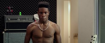 Movie still from “Dope” (2015), directed by Rick Famuyiwa – A young man with a necklace in a room; Close Up shot, Over the shoulder angle