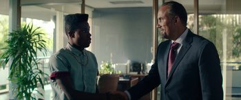 Movie still from “Dope” (2015), directed by Rick Famuyiwa – Two men shaking hands in an office setting; Medium shot, Over the shoulder angle