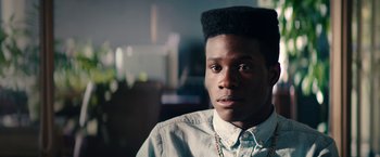 Movie still from “Dope” (2015), directed by Rick Famuyiwa – A man with a very large black afro is looking at the camera; Close Up shot, Over the shoulder angle