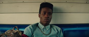 Movie still from “Dope” (2015), directed by Rick Famuyiwa – A man with a beard and a necklace on his head; Close Up shot, Overhead angle