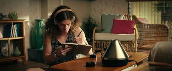 Movie still from “Dope” (2015), directed by Rick Famuyiwa – A woman wearing headphones writing in a notebook; Medium shot, High angle