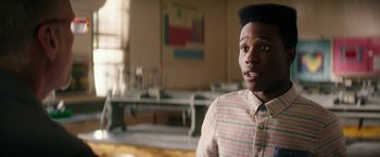 Movie still from “Dope” (2015), directed by Rick Famuyiwa – A man standing in front of a table in a room; Close Up shot, Over the shoulder angle