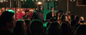 Movie still from “Dope” (2015), directed by Rick Famuyiwa – A group of young men playing instruments at a party; Medium shot, Over the shoulder angle