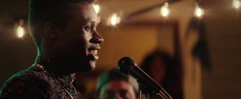 Movie still from “Dope” (2015), directed by Rick Famuyiwa – A man is speaking into a microphone in a room; Close Up shot, Over the shoulder angle