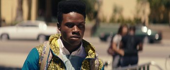 Movie still from “Dope” (2015), directed by Rick Famuyiwa – A young man with an afro stands on the street; Close Up shot, Over the shoulder angle