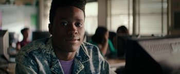 Movie still from “Dope” (2015), directed by Rick Famuyiwa – A young man with blue eyes is smiling for the camera; Close Up shot, Low angle