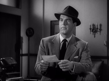 Movie still from “Double Indemnity” (1944), directed by Billy Wilder – A black and white photo of a man in a suit and hat holding a piece of paper; Close Up shot, Low angle