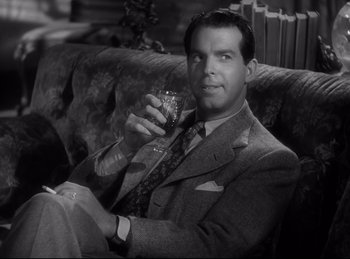 Movie still from “Double Indemnity” (1944), directed by Billy Wilder – A black and white photo of a man sitting on a couch holding a glass; Close Up shot, High angle