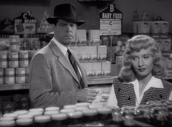 Movie still from “Double Indemnity” (1944), directed by Billy Wilder – A black and white photo of a man and a woman in a grocery store; Medium shot, Over the shoulder angle