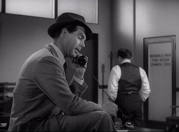 Movie still from “Double Indemnity” (1944), directed by Billy Wilder – A black and white photo of a man talking on a phone; Medium shot, High angle