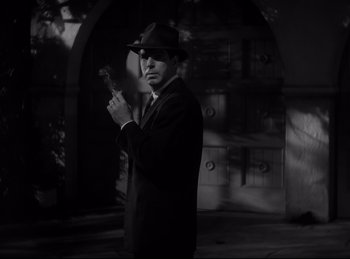 Movie still from “Double Indemnity” (1944), directed by Billy Wilder – A black and white photo of a man in a suit and hat; Medium shot, Low angle
