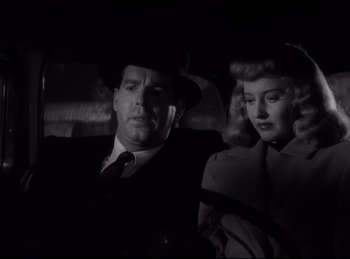 Movie still from “Double Indemnity” (1944), directed by Billy Wilder – A man and a woman are standing next to each other in the dark; Close Up shot, Low angle
