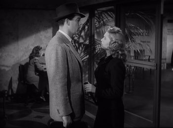 Movie still from “Double Indemnity” (1944), directed by Billy Wilder – A man and a woman standing next to each other in front of a building; Medium shot, Low angle