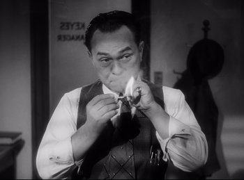 Movie still from “Double Indemnity” (1944), directed by Billy Wilder – A man smoking a cigarette while wearing a tie; Close Up shot, Low angle