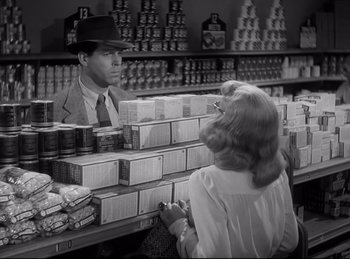 Movie still from “Double Indemnity” (1944), directed by Billy Wilder – A man and a woman are in a grocery store; Medium shot, Over the shoulder angle