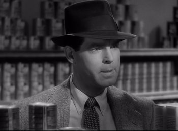 Movie still from “Double Indemnity” (1944), directed by Billy Wilder – A black and white photo of a man wearing a suit and a hat; Close Up shot, Over the shoulder angle