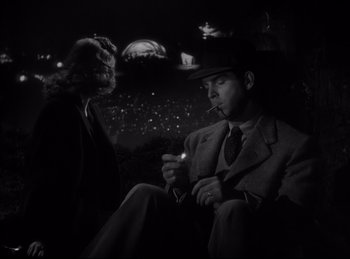 Movie still from “Double Indemnity” (1944), directed by Billy Wilder – A man smoking a cigarette while another man is holding a cigarette holder; Medium shot, High angle