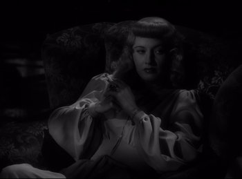 Movie still from “Double Indemnity” (1944), directed by Billy Wilder – A black and white photo of a woman holding a hair brush; Close Up shot, High angle