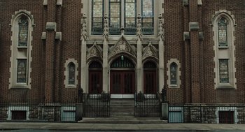 Movie still from “Doubt” (2008), directed by John Patrick Shanley – A large building with stained - glass windows on the side; Extreme Wide shot, Low angle