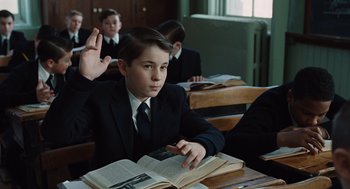 Movie still from “Doubt” (2008), directed by John Patrick Shanley – A boy sitting at a table with a book; Medium shot, Low angle