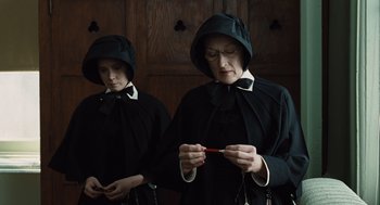 Movie still from “Doubt” (2008), directed by John Patrick Shanley – Two women dressed in black are holding a pair of red scissors; Medium shot, High angle