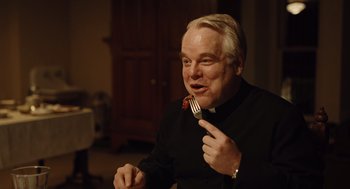 Movie still from “Doubt” (2008), directed by John Patrick Shanley – An older man holding a fork in his mouth; Close Up shot, Over the shoulder angle