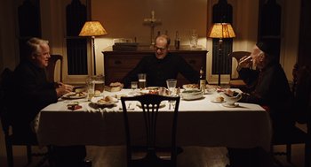 Movie still from “Doubt” (2008), directed by John Patrick Shanley – A man sitting at a table with plates of food; Wide shot, High angle