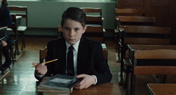 Movie still from “Doubt” (2008), directed by John Patrick Shanley – A boy in a suit and tie sitting at a table; Medium shot, High angle