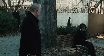 Movie still from “Doubt” (2008), directed by John Patrick Shanley – A man standing next to a tree near a bench; Wide shot, Over the shoulder angle