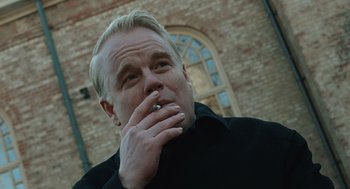 Movie still from “Doubt” (2008), directed by John Patrick Shanley – A man smoking a cigarette in front of a brick building; Close Up shot, Low angle