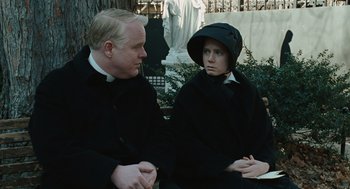 Movie still from “Doubt” (2008), directed by John Patrick Shanley – A man and a woman wearing black clothes and hats; Medium shot, Over the shoulder angle
