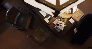 Movie still from “Doubt” (2008), directed by John Patrick Shanley – An overhead view of a desk with a chair and a lamp; Extreme Wide shot, Overhead angle