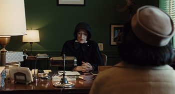 Movie still from “Doubt” (2008), directed by John Patrick Shanley – A woman sitting at a table in front of papers; Medium shot, Over the shoulder angle