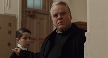 Movie still from “Doubt” (2008), directed by John Patrick Shanley – A man in a priest's outfit stands next to a boy; Close Up shot, Low angle