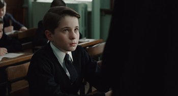 Movie still from “Doubt” (2008), directed by John Patrick Shanley – A young boy in a suit and tie sitting at a table; Close Up shot, Over the shoulder angle