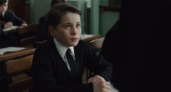 Movie still from “Doubt” (2008), directed by John Patrick Shanley – A boy in a suit and tie sitting at a table; Close Up shot, Over the shoulder angle
