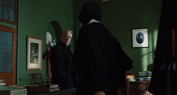 Movie still from “Doubt” (2008), directed by John Patrick Shanley – A man standing in front of a mirror in a room with green walls; Medium shot, Over the shoulder angle