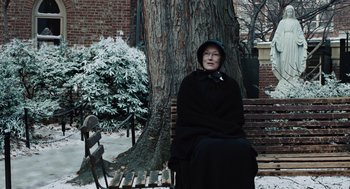 Movie still from “Doubt” (2008), directed by John Patrick Shanley – An older woman sitting on a bench in front of a tree; Wide shot, Over the shoulder angle