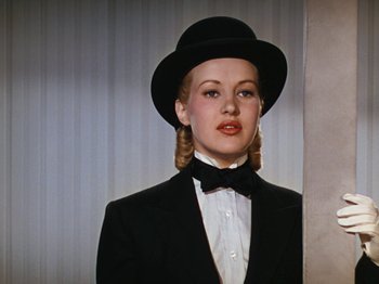 Movie still from “Down Argentine Way” (1940), directed by Irving Cummings – A woman wearing a black suit and a black hat; Close Up shot, Low angle