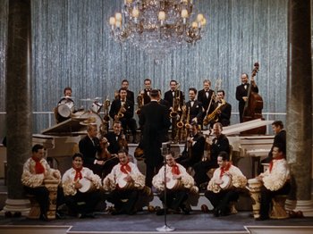 Movie still from “Down Argentine Way” (1940), directed by Irving Cummings – A group of men sitting in front of a microphone; Extreme Wide shot, High angle