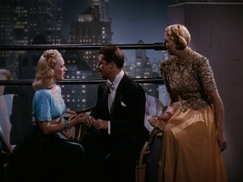 Movie still from “Down Argentine Way” (1940), directed by Irving Cummings – Two women and a man sitting on a chair in front of a building; Medium shot, High angle