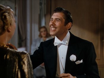 Movie still from “Down Argentine Way” (1940), directed by Irving Cummings – A man in a tuxedo smiling at a woman in a black suit; Medium shot, Over the shoulder angle