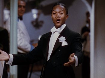 Movie still from “Down Argentine Way” (1940), directed by Irving Cummings – A man in a tuxedo is singing in front of a crowd; Close Up shot, High angle