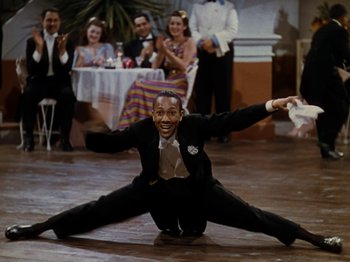 Movie still from “Down Argentine Way” (1940), directed by Irving Cummings – A man sitting on the ground in front of a group of people; Medium shot, High angle